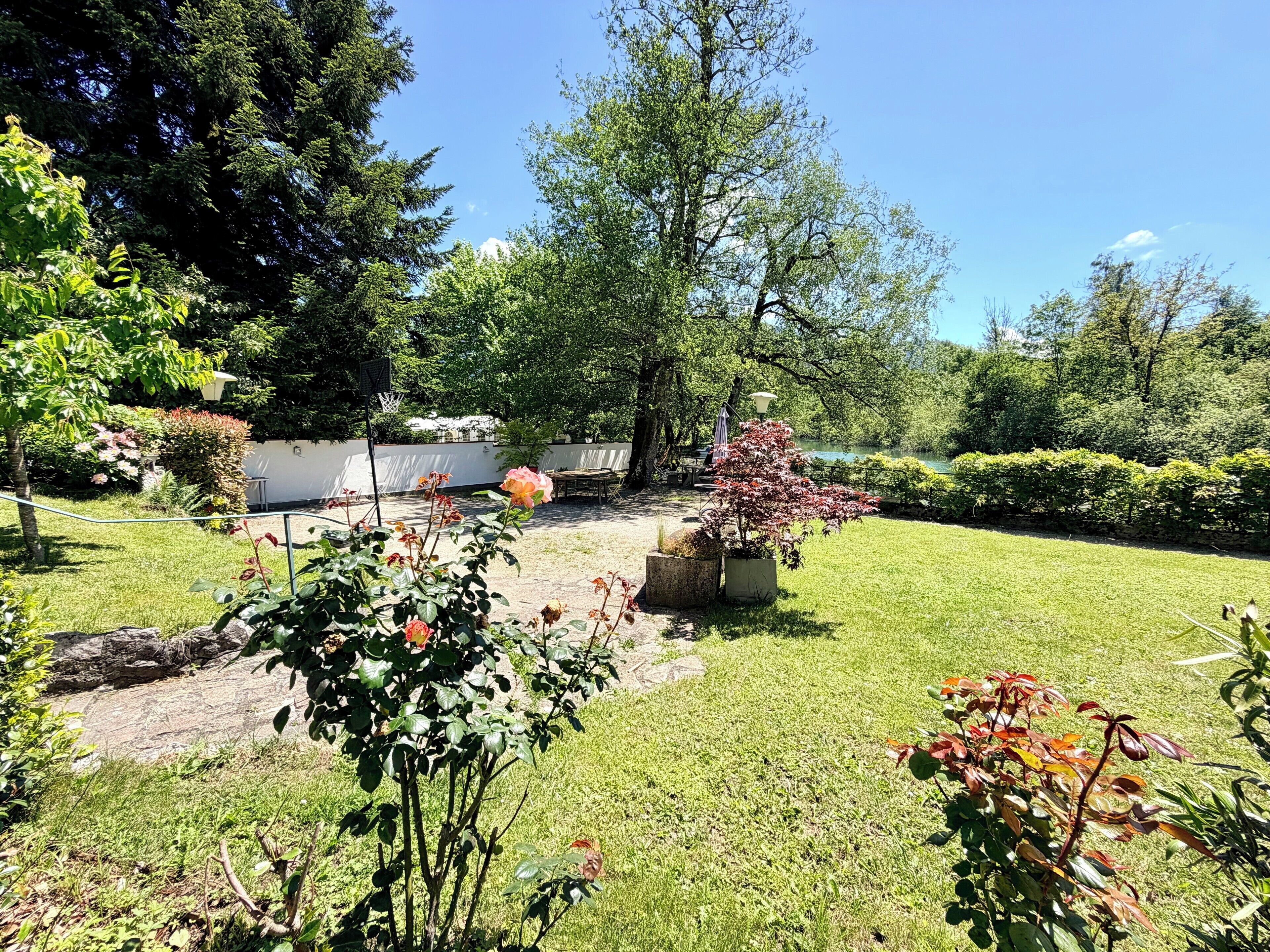 A well-maintained garden with a lawn, potted plants, and a seating area.