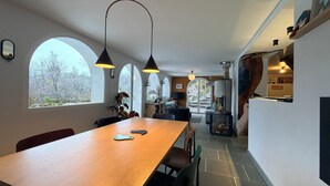 A modern kitchen with a central island, pendant lighting, and a view through large windows.