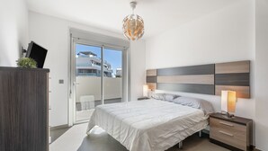 A bedroom with a bed, bedside table, lamp, and a view through a sliding door.