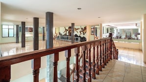 Un vestíbulo amplio con una escalera de madera, techos altos y vista al interior.