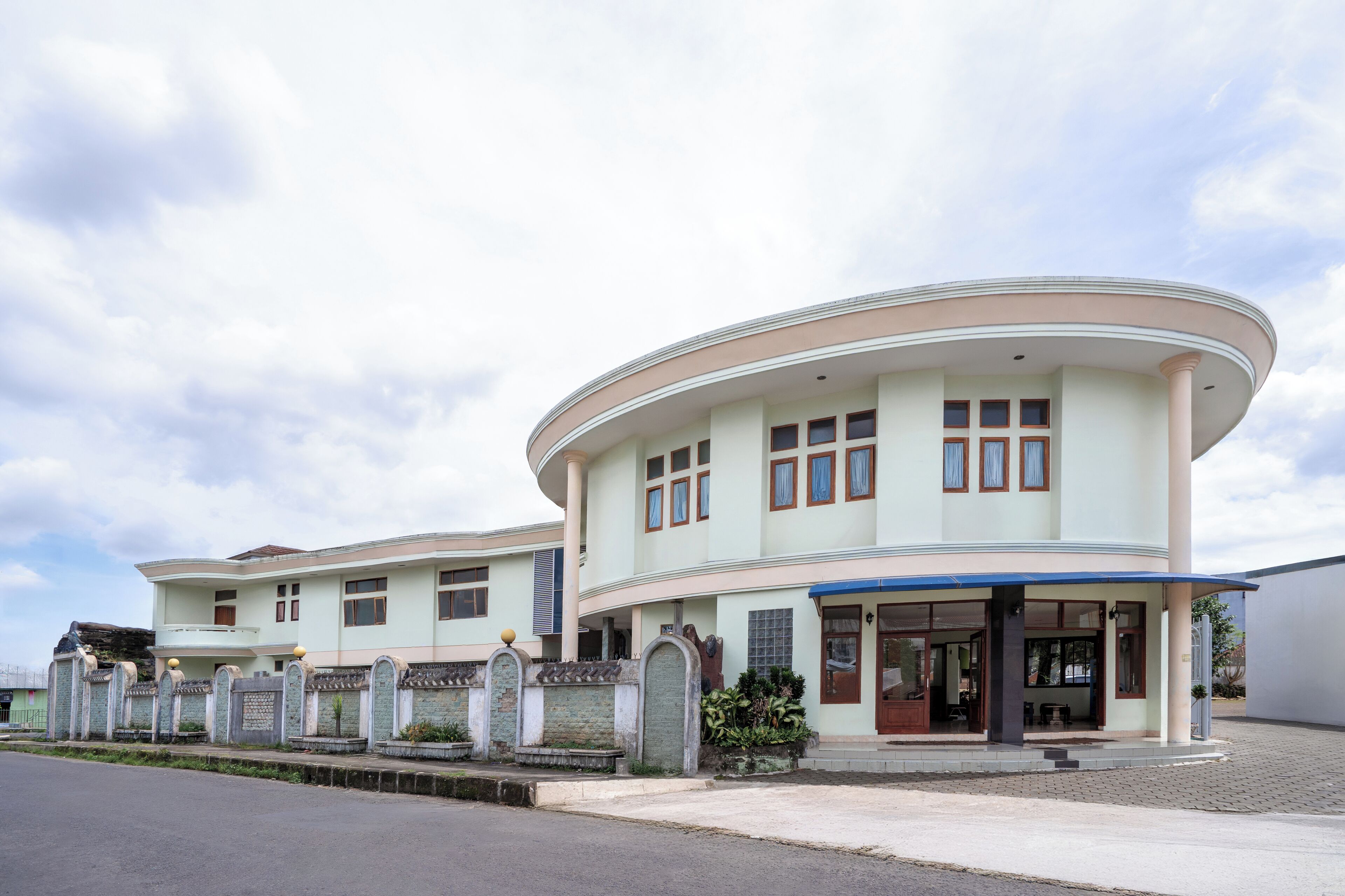 A two-story building with a curved facade, large windows, and a covered entrance area.