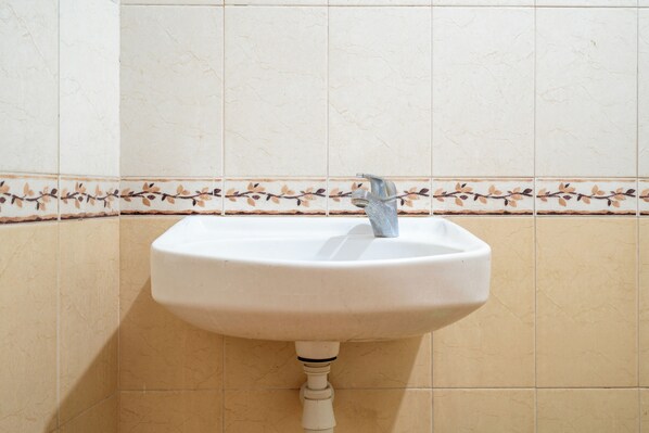 Un lavamanos con lavabo blanco y un solo grifo.
