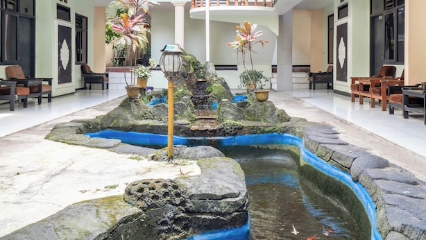 Un patio con fuente, mobiliario y plantas en macetas.
