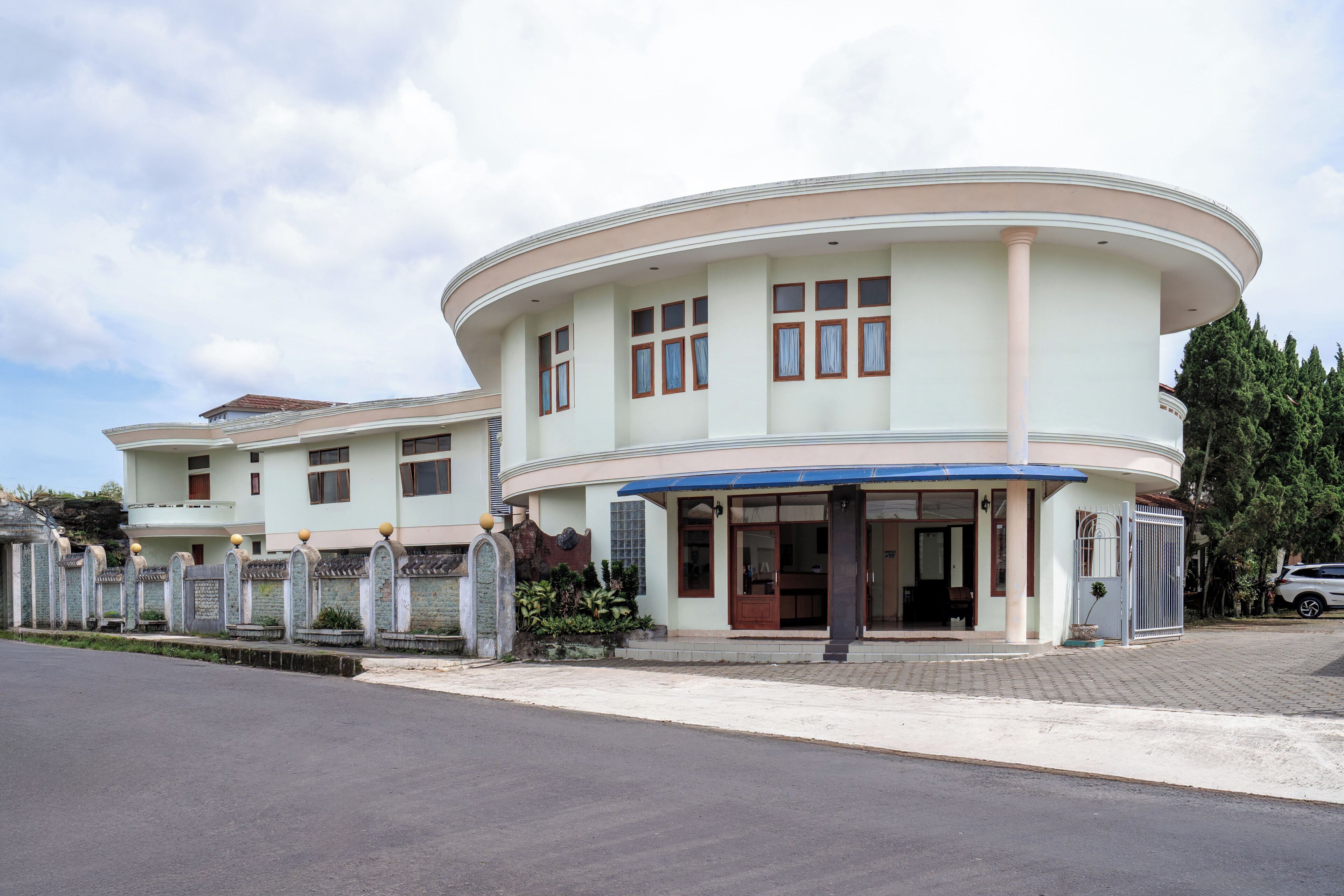A modern building with a curved facade, multiple windows, and a covered entrance.
