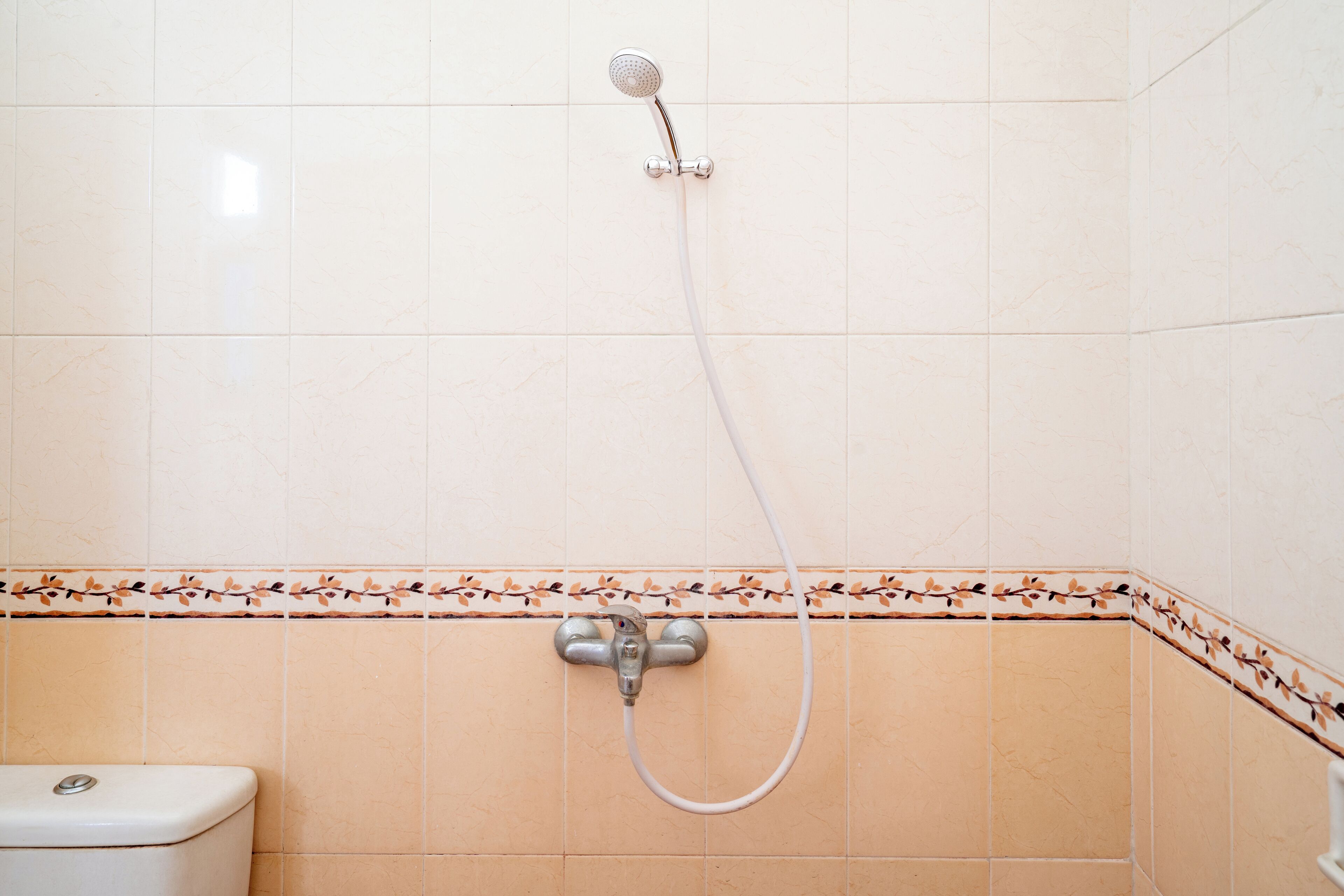 Un baño con ducha, inodoro y detalles decorativos en cerámica.