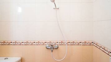 Un baño con ducha, inodoro y detalles decorativos en cerámica.