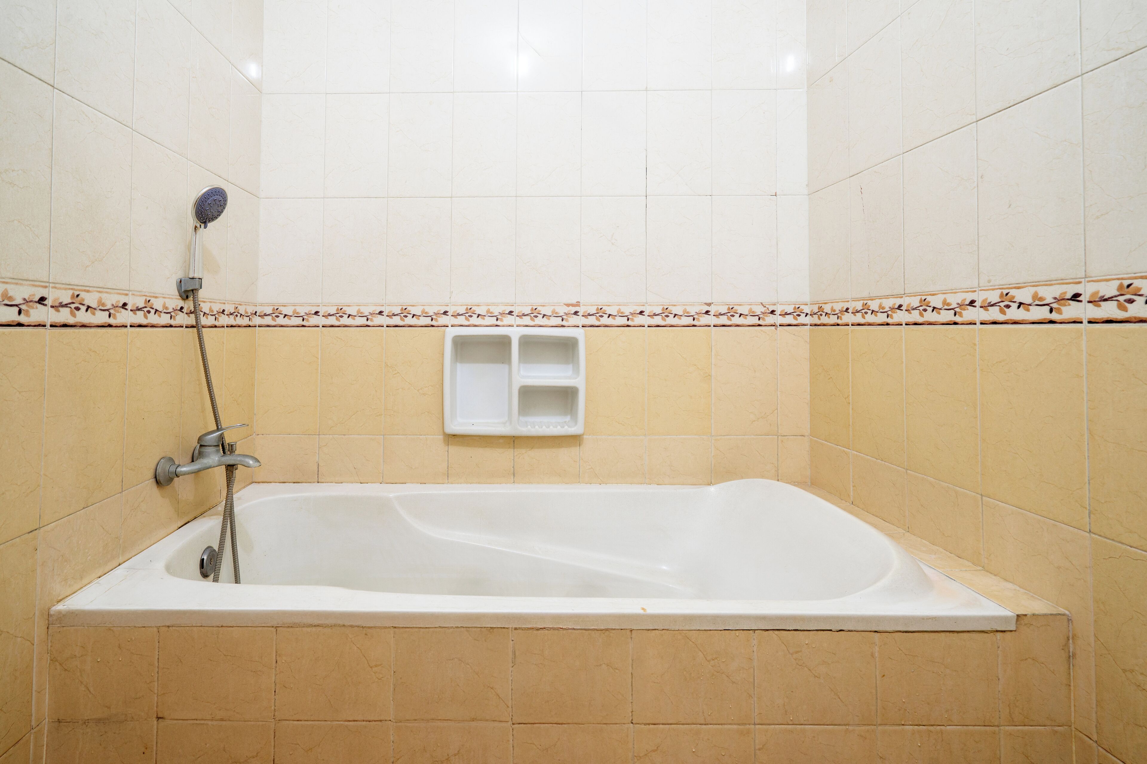 Une salle de bain avec une baignoire, une douche et une petite étagère.