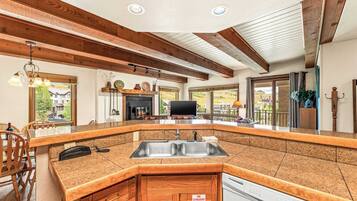 A kitchen with a granite countertop, wooden cabinets, a built-in dishwasher, and a fire extinguisher sign.