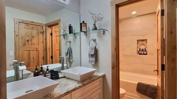A bathroom with two sinks, a large mirror, and a shower area.