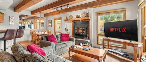 A cozy living room with a fireplace, a television, and a dining area.