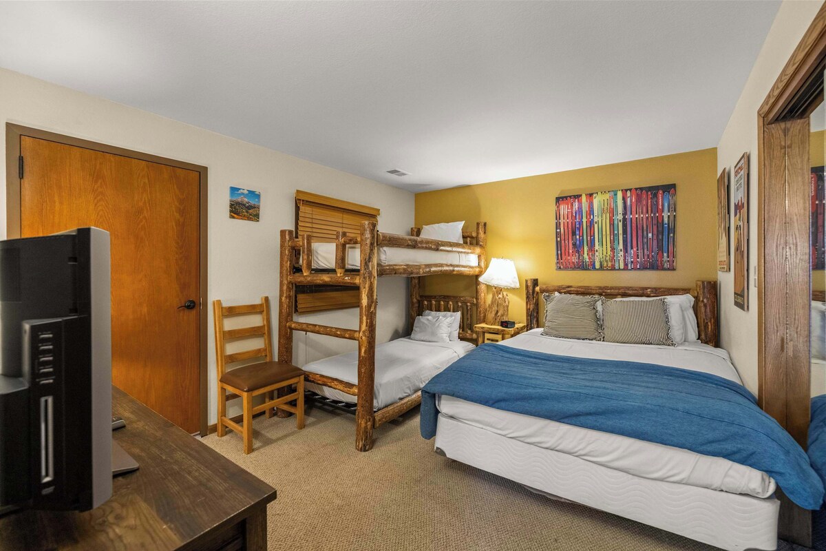 A room with bunk beds, a desk with a television, and a wall with skis.