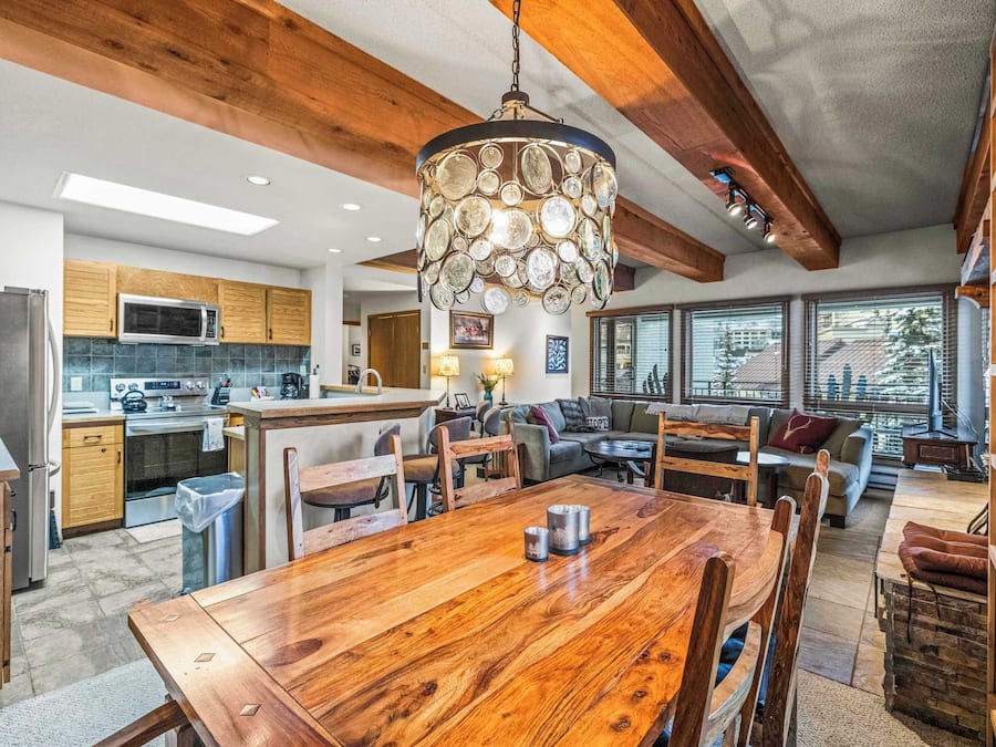 Una cocina amplia con gabinetes de madera, una mesa de comedor y una lámpara colgante.