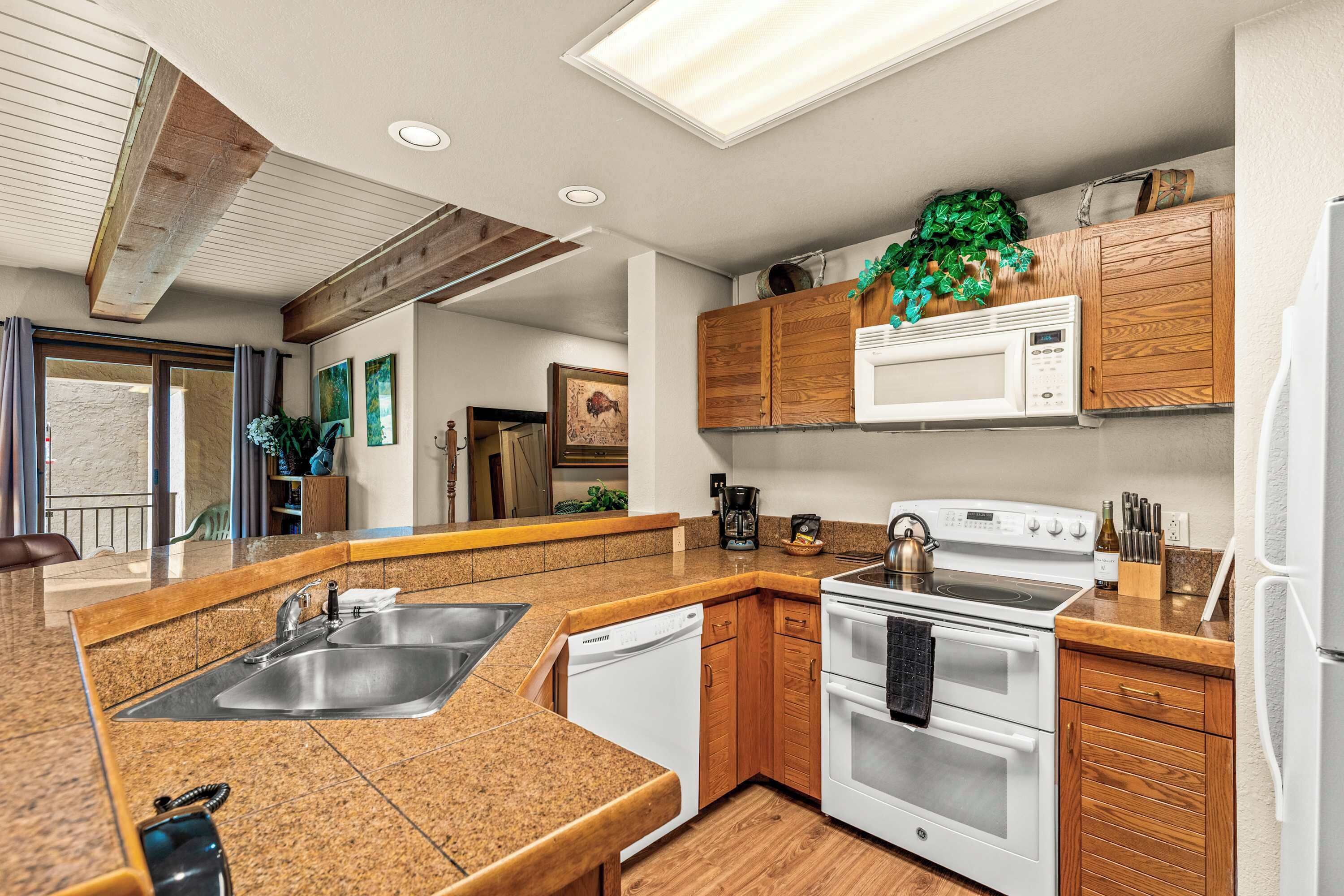 A modern kitchen with granite countertops, stainless steel appliances, wooden cabinets, and a built-in microwave.
