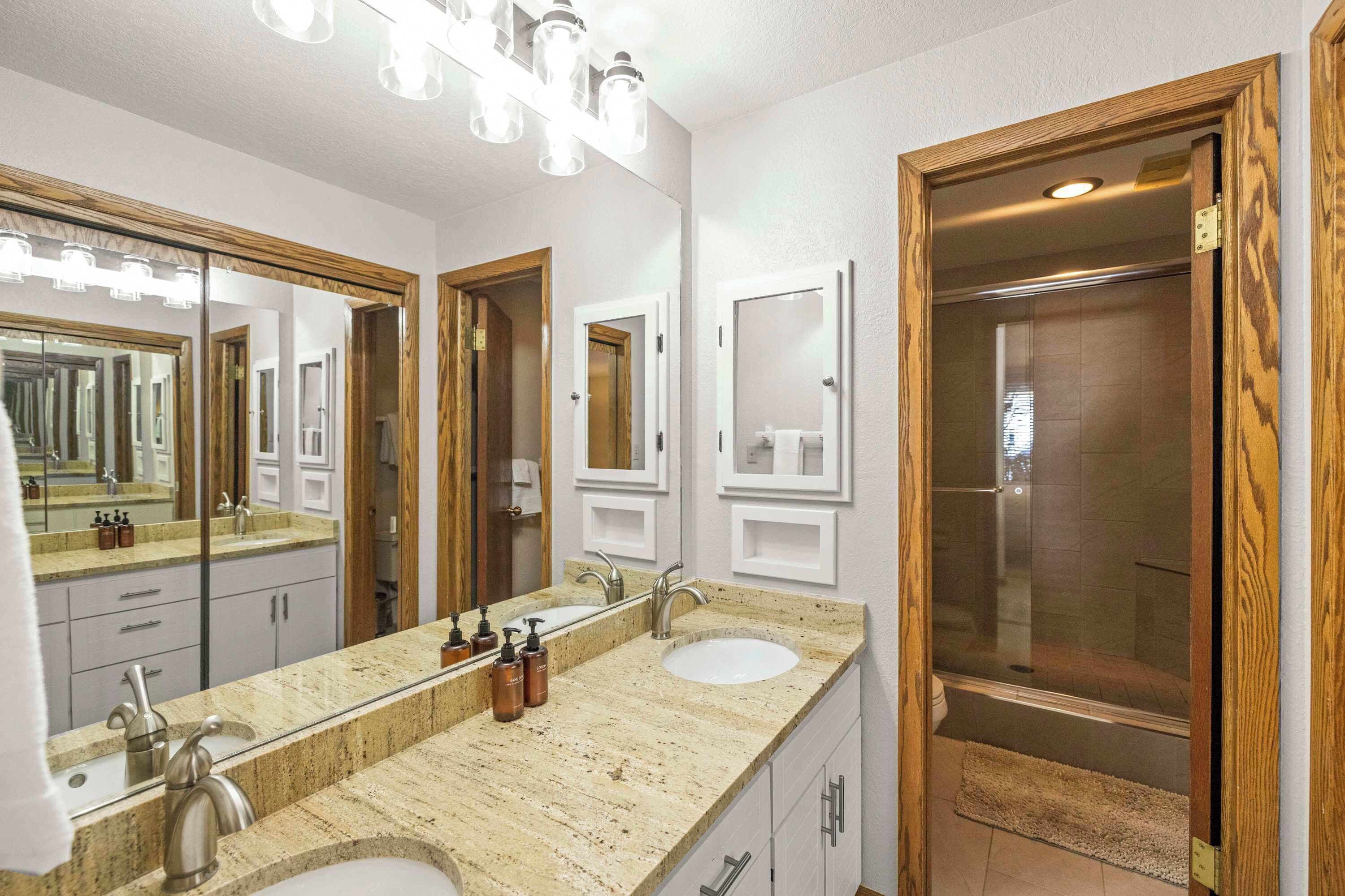 Een badkamer met twee wasbakken, een grote spiegel en een douche.