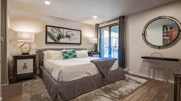 A bedroom with a large bed, two bedside tables, a mirror, and a window with curtains.