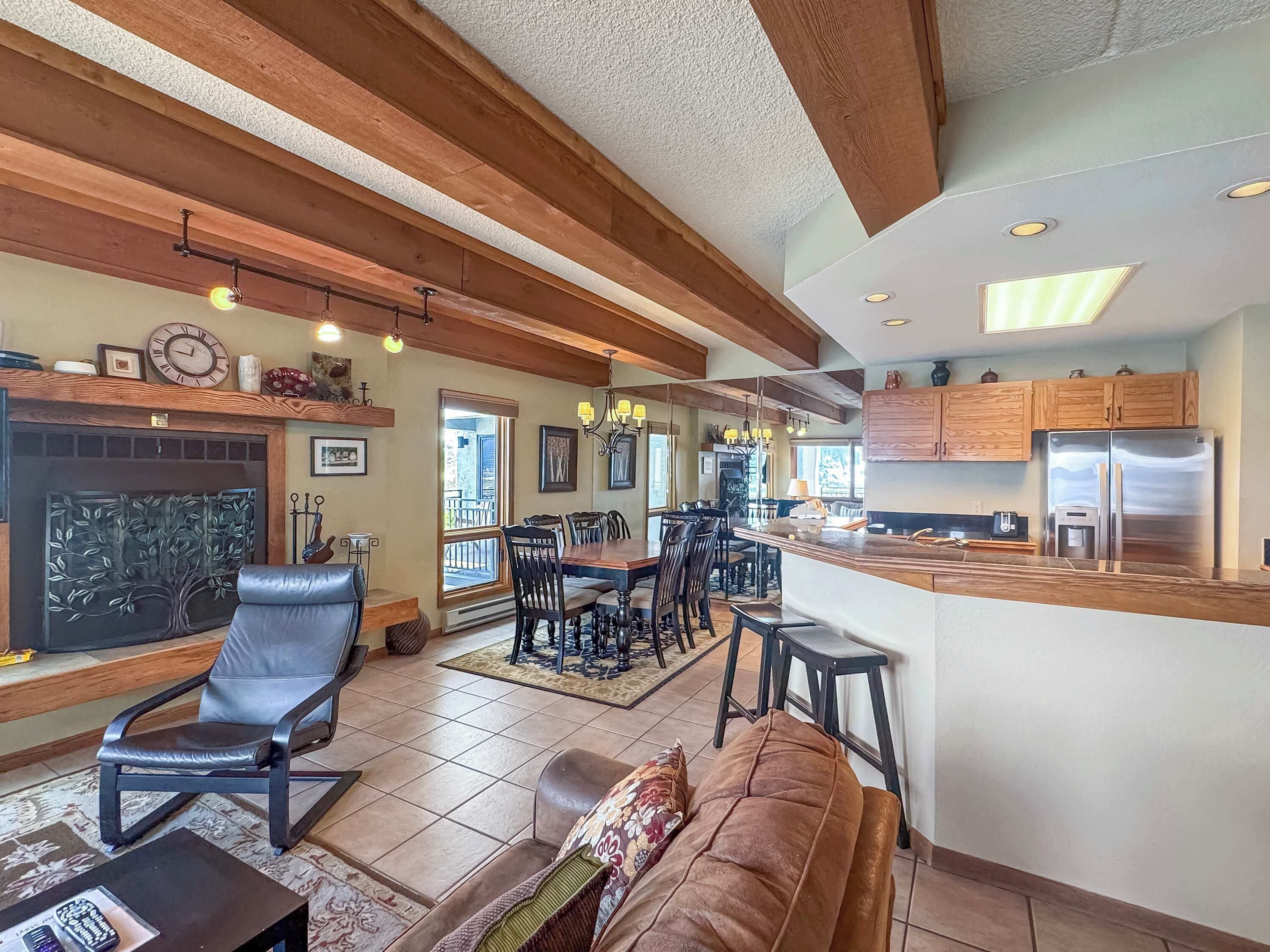A spacious kitchen with a central island, wooden beams, and a dining area with chairs and a sofa.