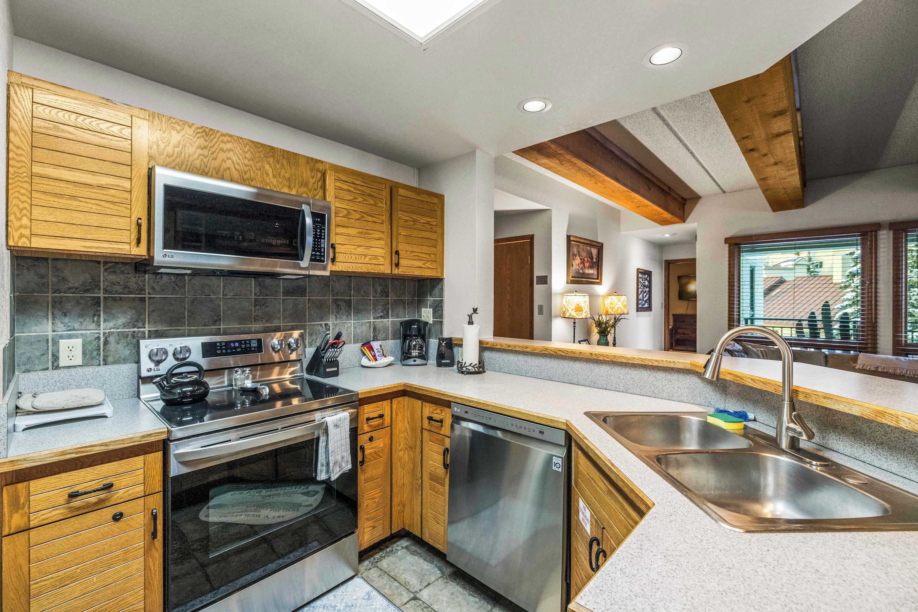 Una cocina moderna con armarios de madera, electrodomésticos de acero inoxidable y un amplio ventanal que proporciona luz natural.