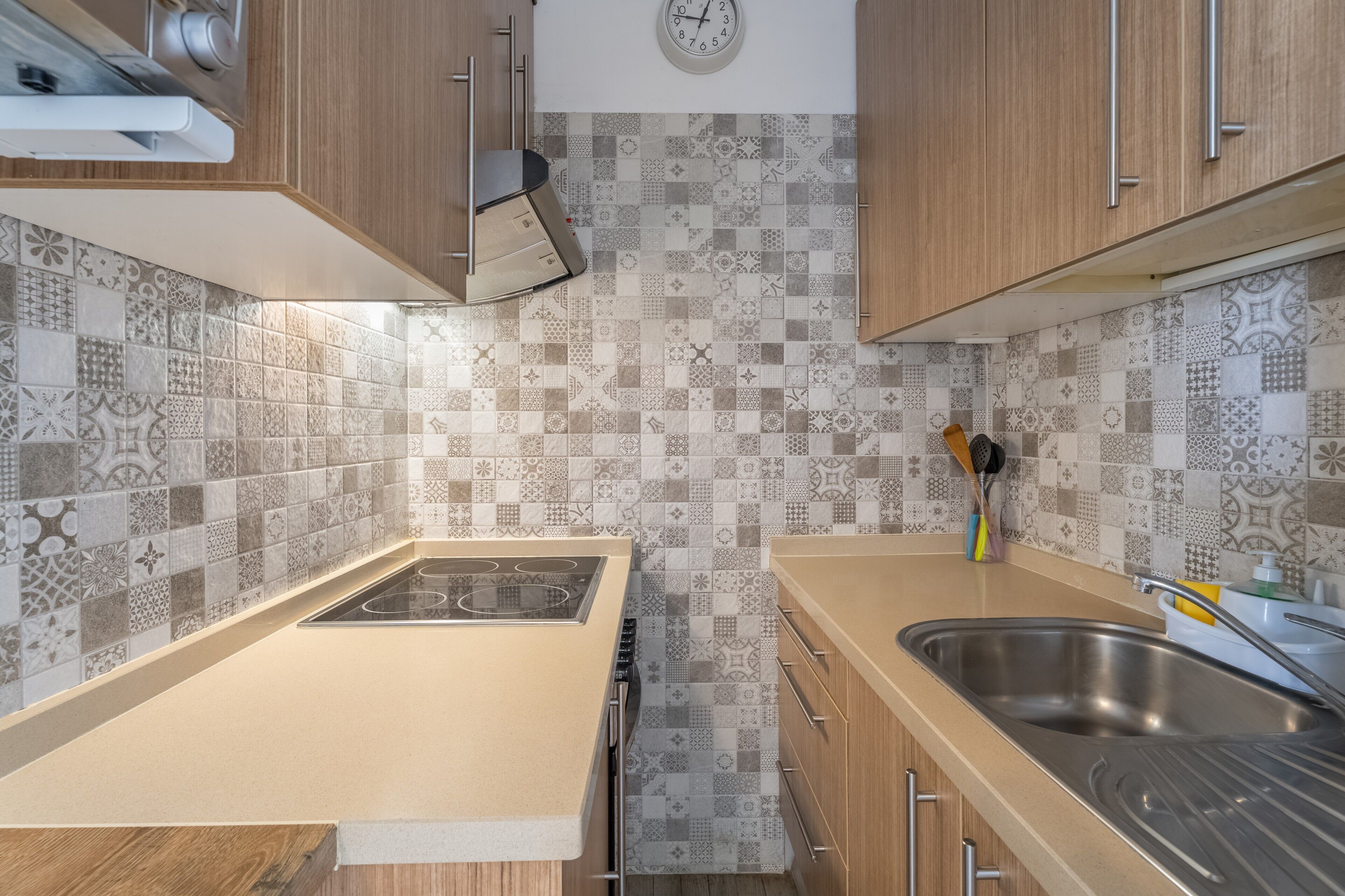 Une cuisine avec des carreaux décoratifs, une cuisinière, un évier et des armoires en bois.