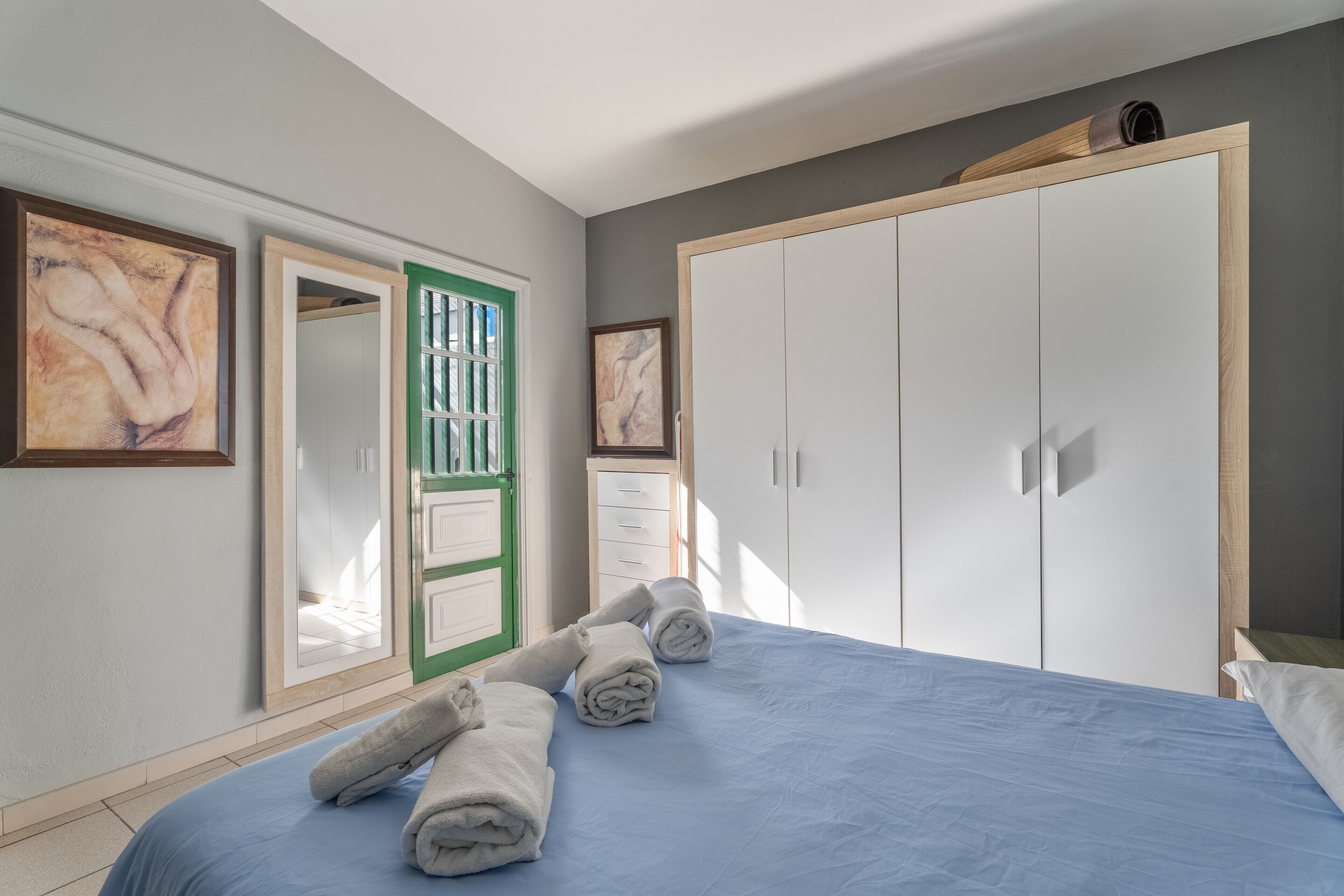 Ein Schlafzimmer mit Bett, Kleiderschrank und Spiegel mit grünem Rahmen.