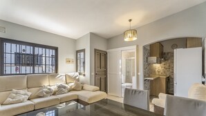 Een moderne woonkamer met een bank, een glazen salontafel en een eethoek met stoelen.
