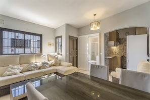 Ein modernes Wohnzimmer mit einer Couch, einem Glastisch und einem Essbereich mit Stühlen.