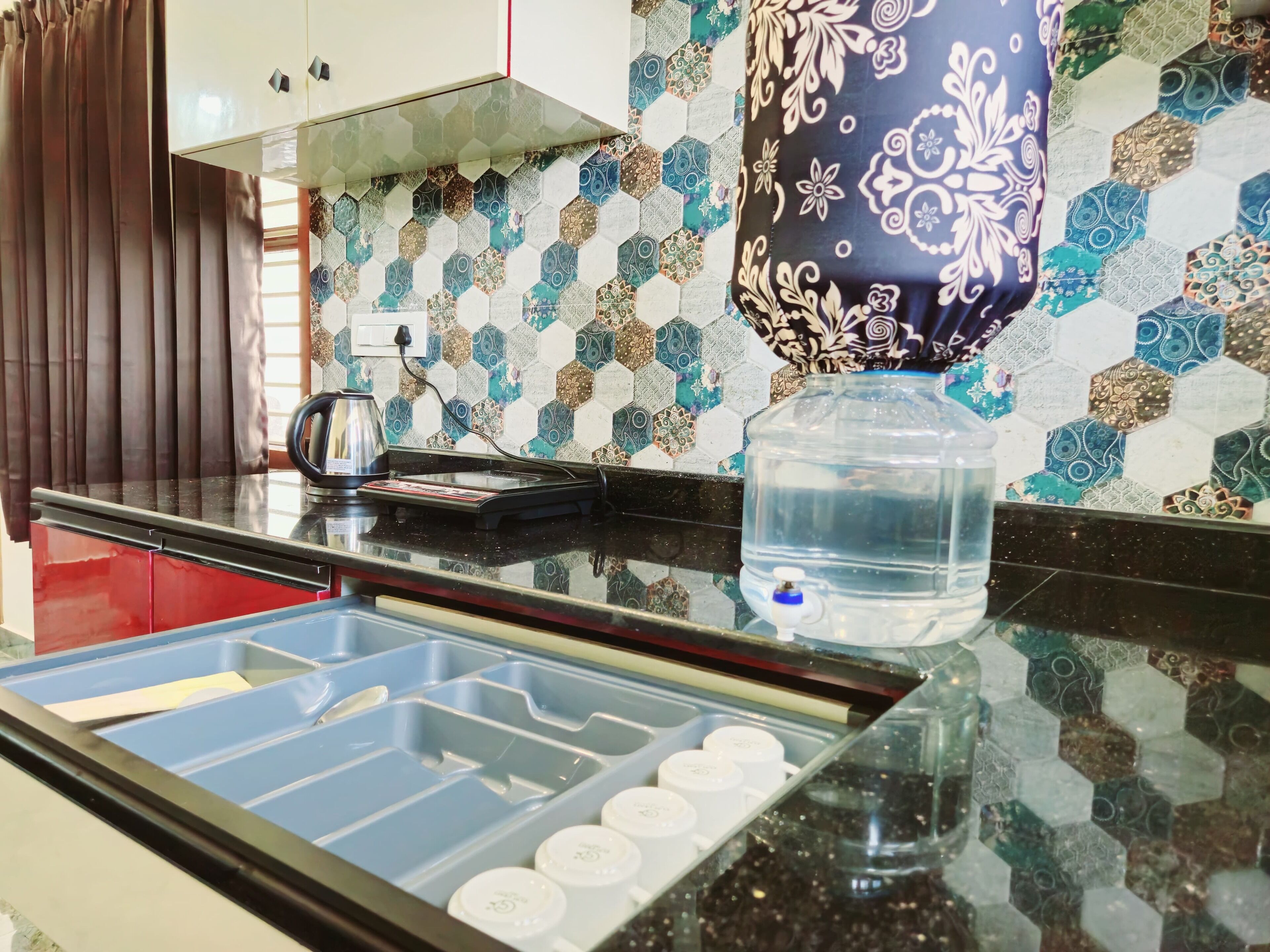 A kitchen with a black countertop, a water dispenser, a kettle, and a toaster.