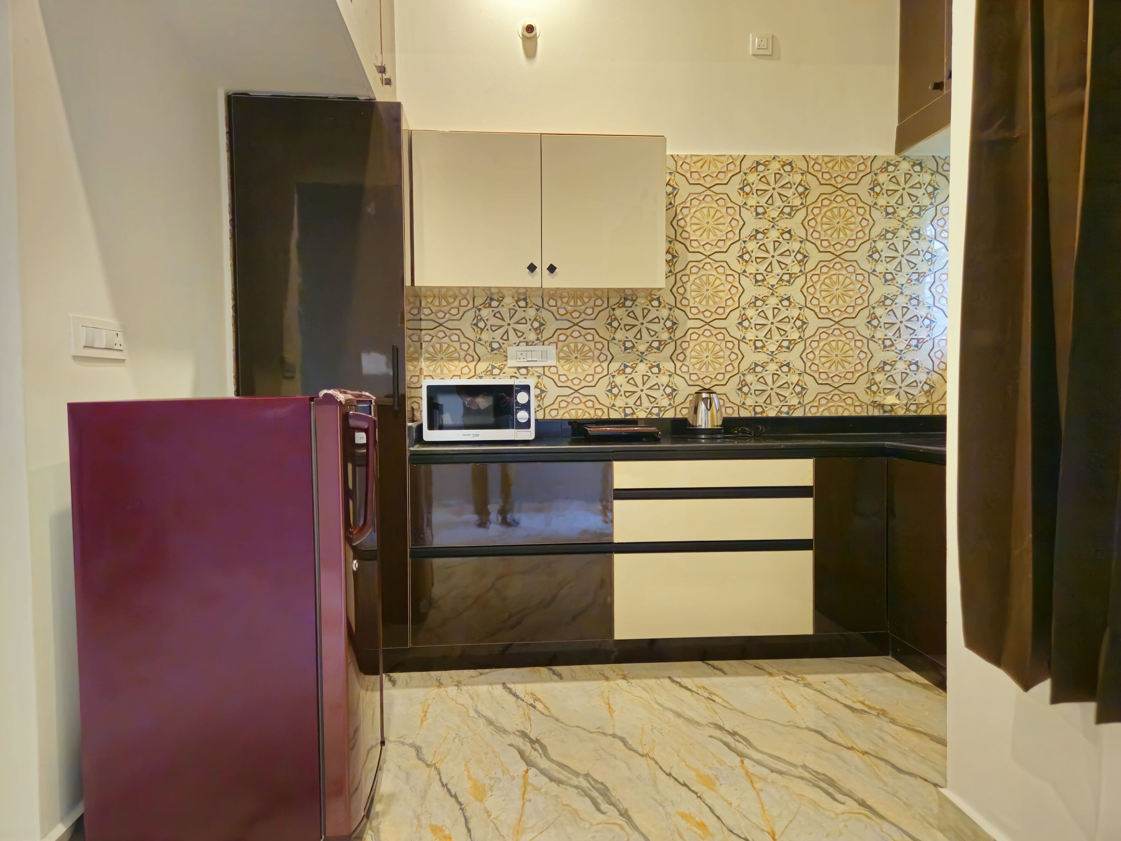 Cocina compacta con refrigerador, microondas y armarios oscuros.