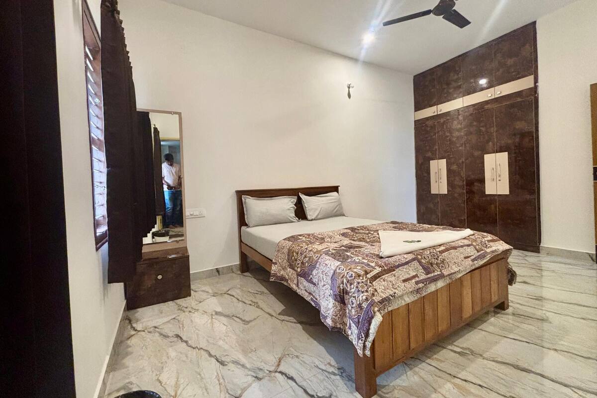 Ein Schlafzimmer mit Bett, Deckenventilator, Kleiderschrank und Spiegel.