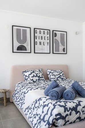 Un letto con una coperta a motivi, due cuscini e asciugamani arrotolati.