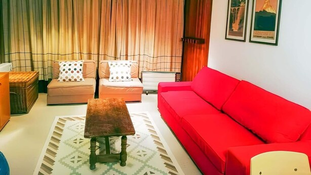 A living room with a red sofa, two armchairs, a small wooden table, and a patterned rug. - Family Stay in Snowy Sierra Nevada (Monachil)