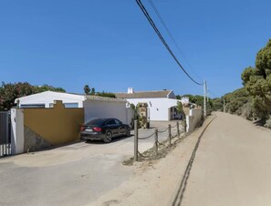 A residential street with a parked car, a white house with a tiled roof, and a clear blue sky. - Couple Retreat in Conil, With a Pool (Conil de la Frontera)