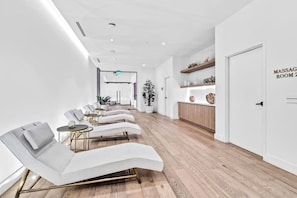 A modern massage room with reclining chairs, a reception desk, and a wooden floor. - Lux 2BD Apt: Stunning Water Views (Miami)