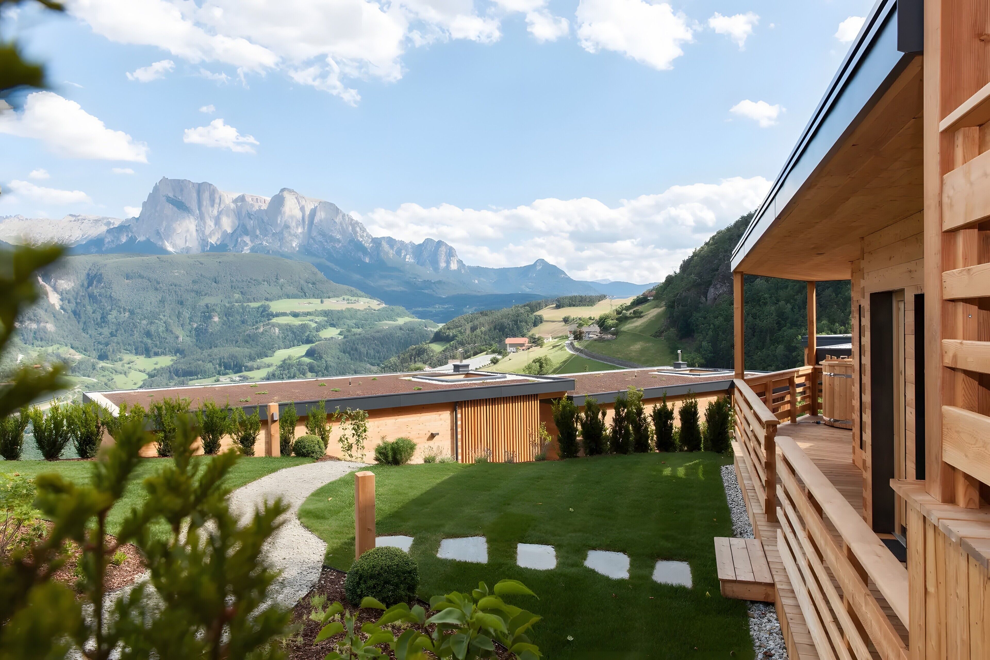A wooden building with a view of mountains and a green lawn.
