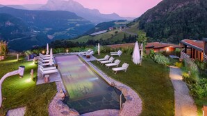 A pool area with lounge chairs, a wooden deck, and a view of mountains. - Chalet 'Pennhof  Castanea 3' with Mountain View, Private Terrace and Wi-Fi (Barbian)