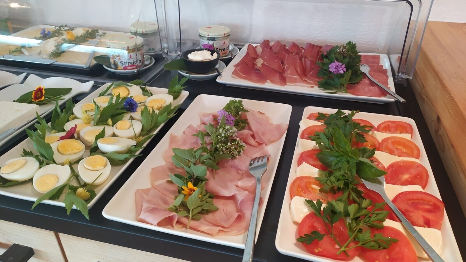 Een buffet met diverse gerechten, waaronder vleesschotels, eieren en tomaten.