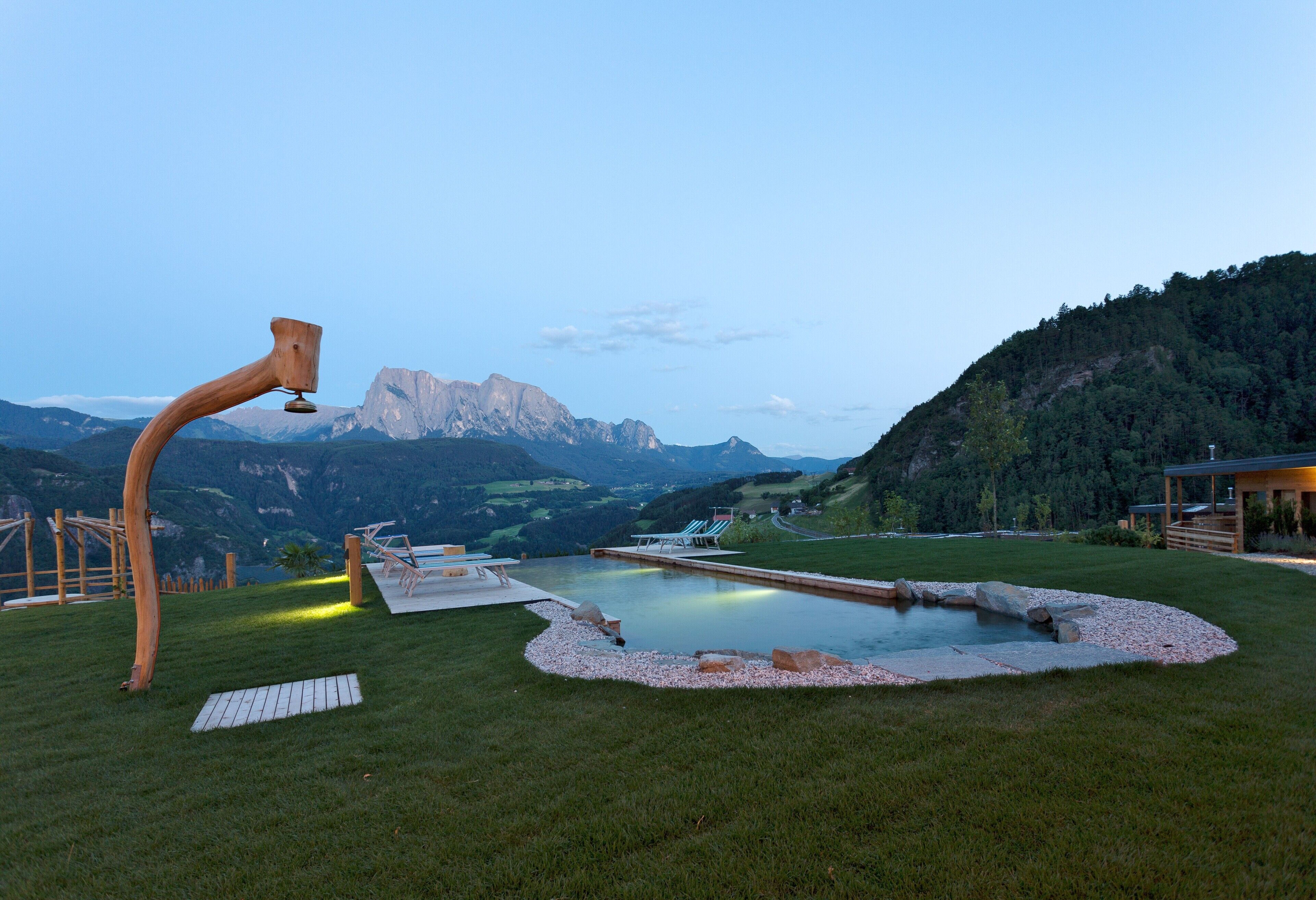 Ein Pool mit einer Holzkonstruktion, einer Liege und Blick auf die Berge.