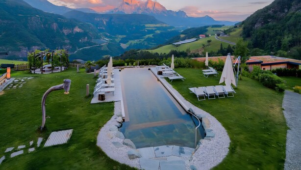Ein Pool mit Blick auf Berge, Liegestühle und ein Garten.