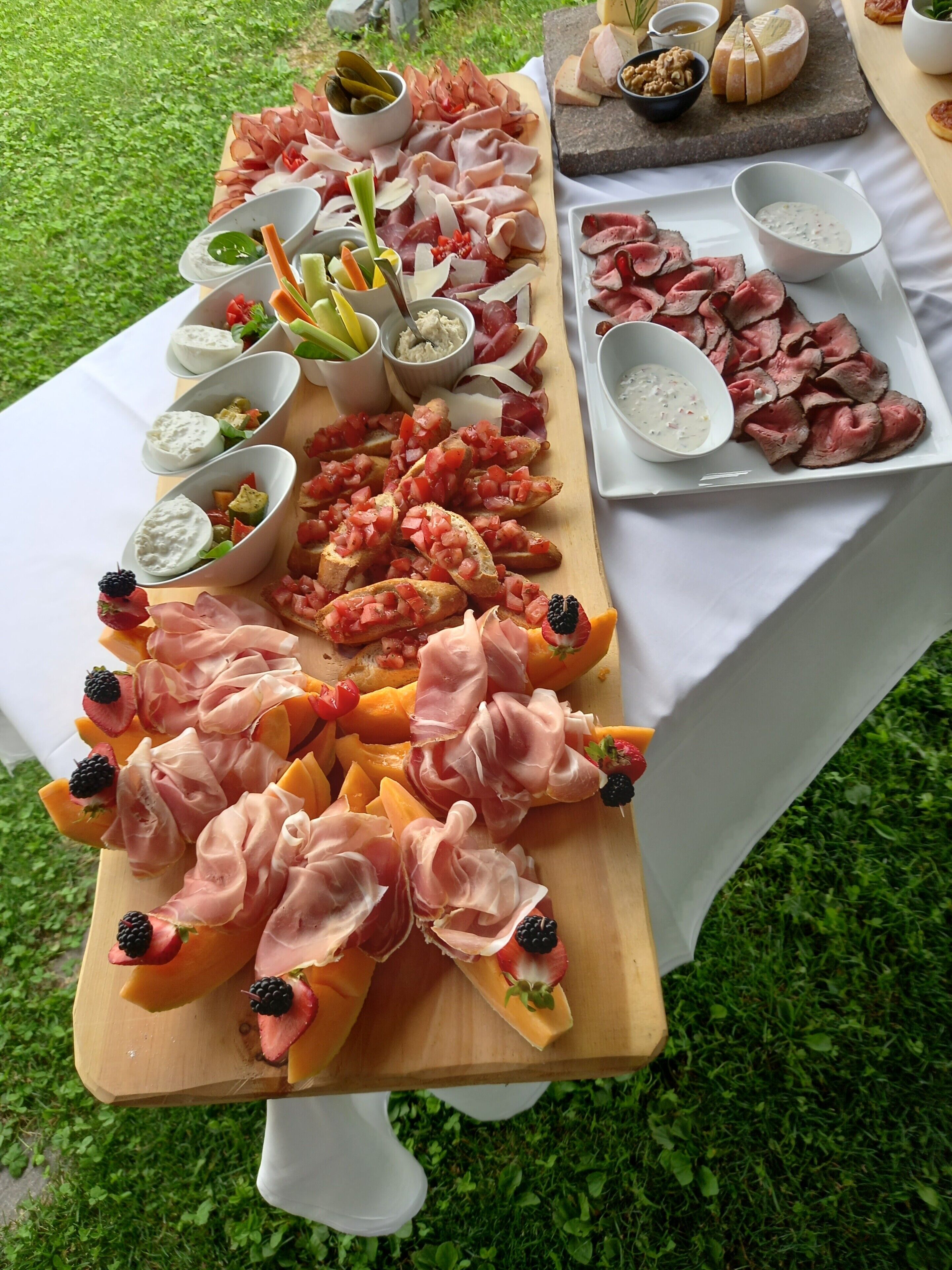 Una mesa con diversos alimentos, incluyendo carnes, quesos y salsas.