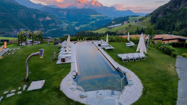 A pool with a view of mountains, lounge chairs, and a garden. - Room 'Hotel Pennhof Rubis' with Mountain View, Shared Pool and Wi-Fi (Barbian)