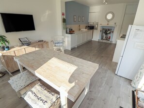 A modern kitchen with a wooden table, white cabinets, and a flat-screen TV mounted on the wall. - The Seaside Retreat (Mablethorpe)