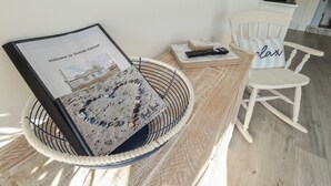 A room with a bed, a bedside table with a remote control, a framed welcome sign, and a white chair. - The Seaside Retreat (Mablethorpe)