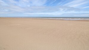 A wide sandy beach with a clear sky and gentle waves. - The Seaside Retreat (Mablethorpe)
