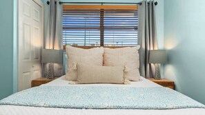 A bedroom with a bed, two nightstands, a window with blinds, and a view of the outdoors. - Seaside Beach & Racquet Club 1115 (Orange Beach)