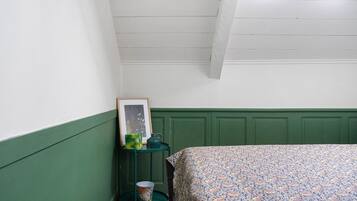 Una camera da letto con pannelli decorativi verdi, una coperta con motivo, un tavolino con una cornice e un lampadario verde.