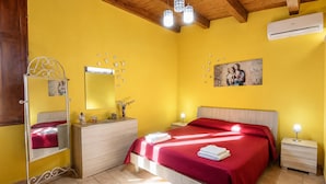 Ein Zimmer mit einem Bett, Nachttischen, einer Kommode, einem Spiegel und einer Klimaanlage.