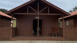 Een houten blokhut met een schuin dak, een deur en een klein terras.