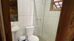 Een kleine badkamer betegeld, met toilet, wastafel en douche.