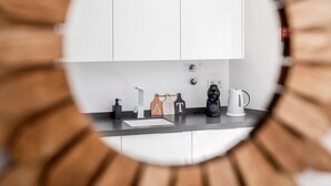 A sunburst mirror reflecting a kitchen area with cabinets, a coffee maker, and a kettle. - Portimao riverview T2 luxe 1st floor with Balcony, Wi-Fi and Air Conditioning (Portimão)