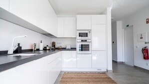 A modern kitchen with white cabinetry, a black countertop, a built-in microwave, and an oven. - Portimao riverview T2 luxe 1st floor with Balcony, Wi-Fi and Air Conditioning (Portimão)