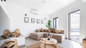 A modern living room with a sectional sofa, a round coffee table, and a large window offering a city view. - Portimao riverview T2 luxe 1st floor with Balcony, Wi-Fi and Air Conditioning (Portimão)